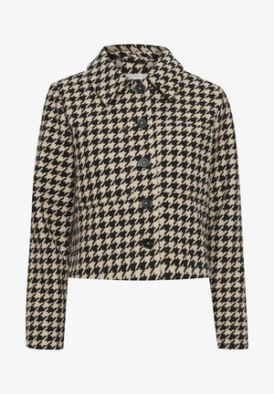 Kaksivärinen houndstooth-kuvioinen cropped-takki vaaleanbeige ja musta, jossa on pyöreä kaulus, etupainonapit ja vasemmalla puolella applikoitu tasku.