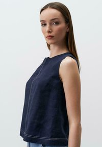 Top senza maniche blu navy con scollatura rotonda, dettagli delle cuciture verticali e una vestibilità leggermente ampia. Realizzato in un tessuto testurizzato e leggero.