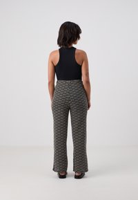 Black sleeveless top paired with high-waisted, wide-leg pants featuring a black and white textured pattern. Smooth fabric with subtle sheen.