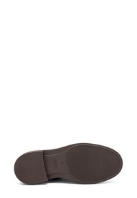 Suela de zapato marrón con agarre texturizado, punta redondeada y tacón rectangular, mostrando el nombre de la marca y la talla estampados cerca del tacón.