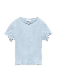 Světle modrý top s krátkým rukávem vyrobený z texturované tkaniny. Má kulatý výstřih a volánkové okraje na rukávech a lemu.