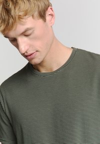 Grijs gestreept t-shirt van zachte katoen met een ronde halslijn. De strepen zijn dun en gelijkmatig verdeeld, en bedekken de gehele voorkant.