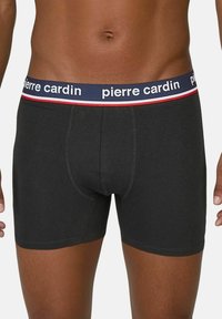 Zwarte katoenen boxershorts met een aansluitend ontwerp, voorzien van een marineblauwe tailleband met witte letters en rode accentstrepen.