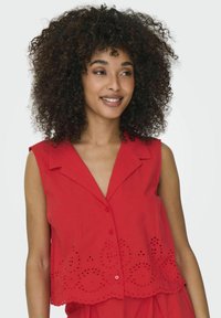 Blusa rossa senza maniche con scollatura a V, chiusura frontale con bottoni e design ad occhietto ricamato sull'orlo. Tessuto morbido con una vestibilità casual.