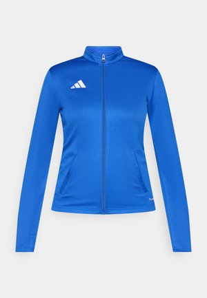 Veste de sport bleue avec un col montant, des manches longues et une fermeture éclair à l'avant. Comprend deux poches latérales et un logo blanc sur le côté gauche de la poitrine.