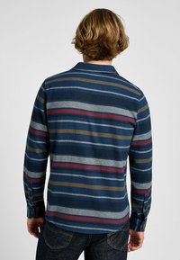 Camicia a maniche lunghe da uomo in blu navy con righe orizzontali rosse, verdi e grigie. Presenta un colletto button-down e un tessuto testurizzato.