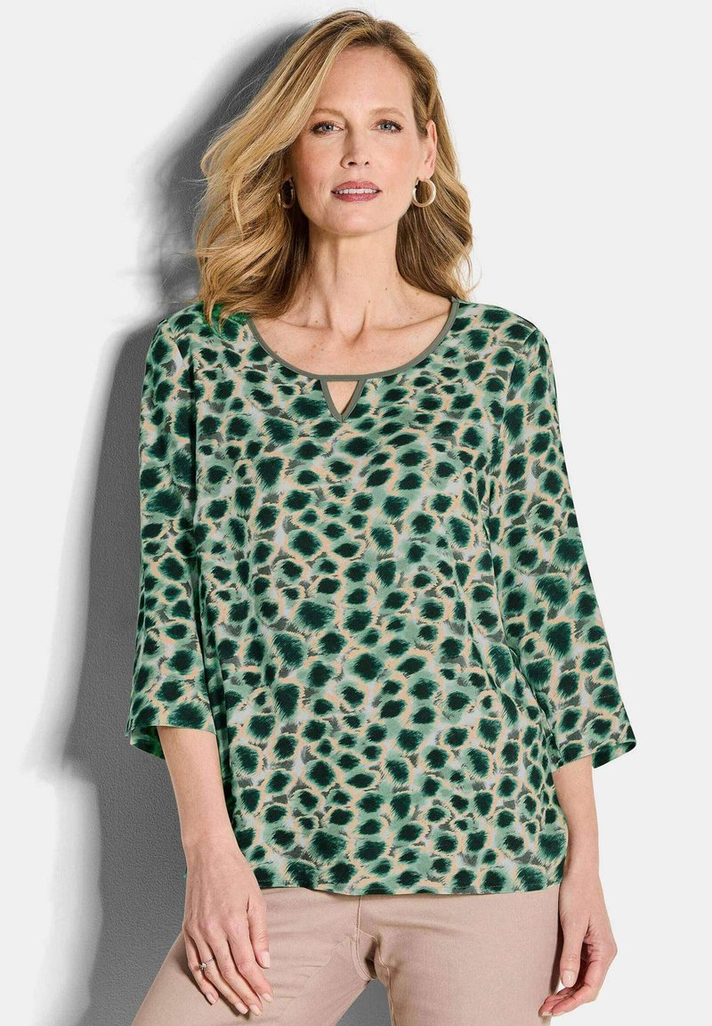 Groene en tan luipaardprint top met een ronde hals, driekwartmouwen en een sleutelgat uitsparing aan de voorkant. Gladde textuur.