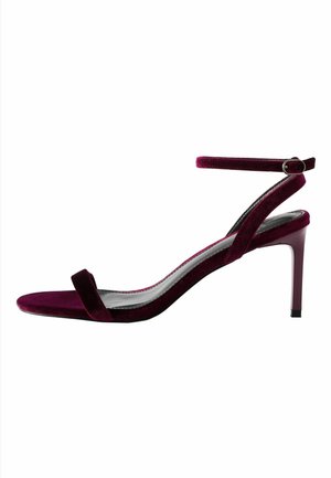 Sandale à talon haut en velours violet foncé avec bride à la cheville et talon fin sur fond blanc.