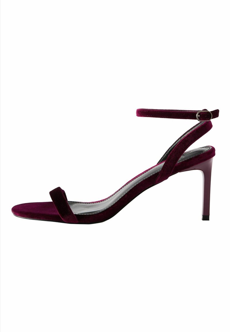 Sandale à talon haut en velours violet foncé avec bride à la cheville et talon fin sur fond blanc.