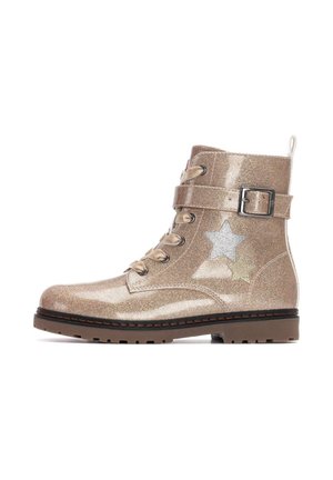 Botín dorado brillante con cordones en la parte frontal, una correa con hebilla y detalles de estrellas en plata y verde. Suela de goma para mayor tracción.