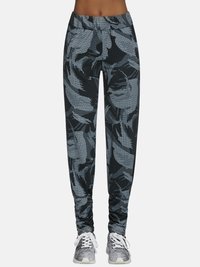 Czarno-szare spodnie dresowe z wzorem, z elastycznym pasem, ozdobione motywem liści i zwężane ku dołowi, zestawione z szarymi trampkami.