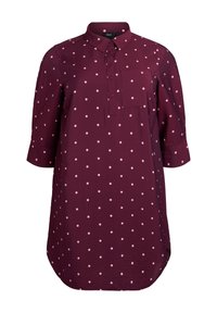 Burgundy skjorta med vita prickar, knappp front, krage, långa ärmar och bröstficka. Sömmen har en rundad kant. Lättviktsmaterial.
