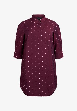 Burgundy shirt with white polka dots, button-up front, collar, long sleeves, and a chest pocket. Hem has a rounded edge. Lightweight fabric.