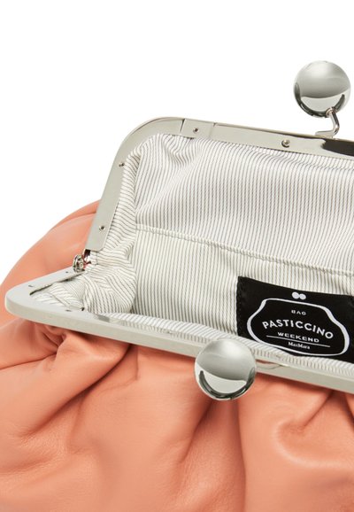 Borsa a tracolla in pelle pesche con una struttura in metallo e chiusura a scatto, dotata di foderatura divisa in bianco con sottili righe grigie e un'etichetta nera.
