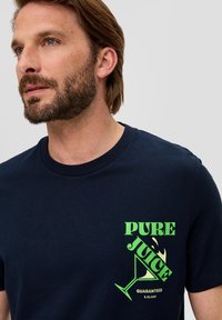 Navy katoenen T-shirt met een grafische print van "PURE JUICE" in groene tekst en een ontwerp van een cocktailglas. Korte mouwen, ronde hals.
