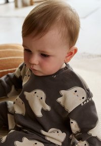 Halli pikkade varrukatega särk valgete kummitusemotiividega, millel on õrnad roosakad põsed ja varrukal valge sõna "BABY". Pehme kangatüüp.