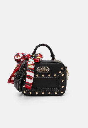 Sac à main Moschino noir avec clous dorés, poignée supérieure, fermeture éclair et un foulard rouge à motifs décoratifs attaché à la poignée.
