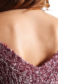 Gestrickter Pullover mit tiefem V-Ausschnitt, in einer Mischung aus Bordeauxrot und Creme, mit strukturiertem Muster und weichem, dickem Garn.