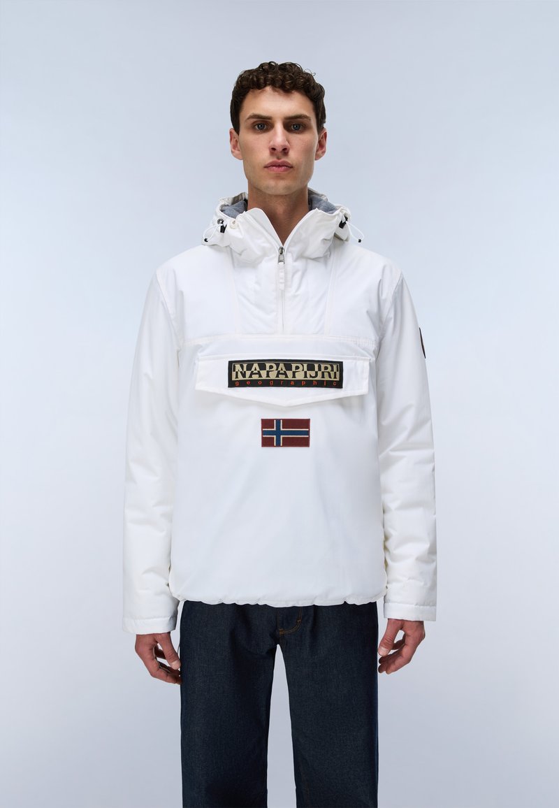 Junger Mann trägt eine weiße Kapuzenjacke mit Frontreißverschluss, Napapijri-Logo und norwegischem Flaggen-Patch, kombiniert mit dunkelblauen Jeans.