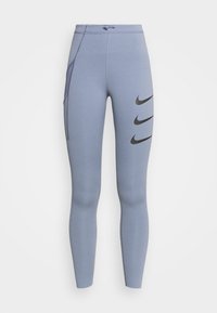 Leggings de sport bleus en tissu extensible, dotés d'une taille haute, d'une poche latérale et de trois logos Nike noirs sur le côté gauche.