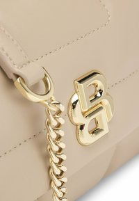 Borsa a mano in pelle beige con una catena dorata e un evidente dettaglio con il logo dorato. Le cuciture delineano la forma strutturata della borsa.