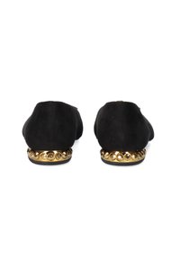 Zapatos de ante negro tipo slip-on con punta redonda y una plataforma con acentos dorados que presenta tachuelas redondas a lo largo de la base.
