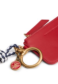 Portafoglio portachiavi in pelle rossa con accessori in metallo color oro, cinturino intrecciato blu navy e bianco, logo in rilievo e charm rotondo con iniziali.