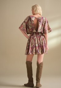 Mitmevärviline paisley-mustriga kleit tagaküljel lõikega, lühikeste puffvarrukatega ja soonikkoes vöökohaga. Ühitatud pruunide seemisnahast põlvikutega.
