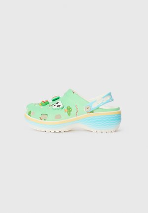 Green clog with decorative animal charms, a textured upper, and a wavy blue sole. Features holes for breathability and a back strap.