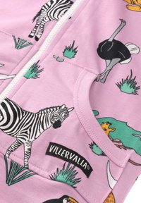 Zippered lightweight hoodie in pink fabric, adorned with black and white animal prints, including zebras and ostriches, featuring a pocket and logo.