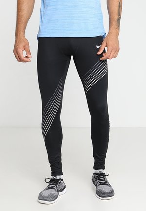 Sorte athletic leggings med en glat tekstur og en tætsiddende design. Har hvide diagonale striber på siderne, parret med en blå top.
