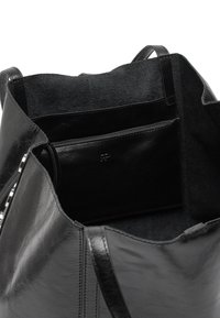 Czarna skórzana torba typu tote z miękkim wnętrzem, kieszenią na zamek błyskawiczny i gładką teksturą. Wytrzymałe rączki i bezszwowa konstrukcja.