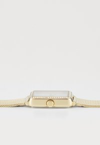 Montre-bracelet rectangulaire en or avec un cadran serti de diamants et un bracelet en mailles, présentée de côté avec la couronne visible sur fond blanc.