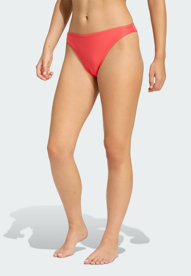 Koronkowe bikini w kolorze koralowym o niskim stanie, wykonane z gładkiego materiału. Posiada czyste krawędzie i minimalne krycie dla komfortu.