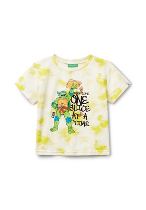 Světle žluté tričko s krátkým rukávem s tie-dye vzorem, na kterém je grafika zelené postavy držící kousek pizzy a text "Vnímej život po jednom plátku."