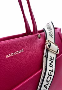 Borsa tote in pelle fucsia con manici piatti, caratterizzata da un logo dorato e una tracolla a righe staccabile con scritta nera.