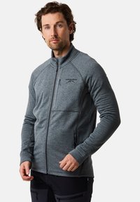 Grijze zip-up jas met een tekstuurpatroon, hoge kraag en een borstzak. Beschikt over platlock naden en subtiele logo-details.
