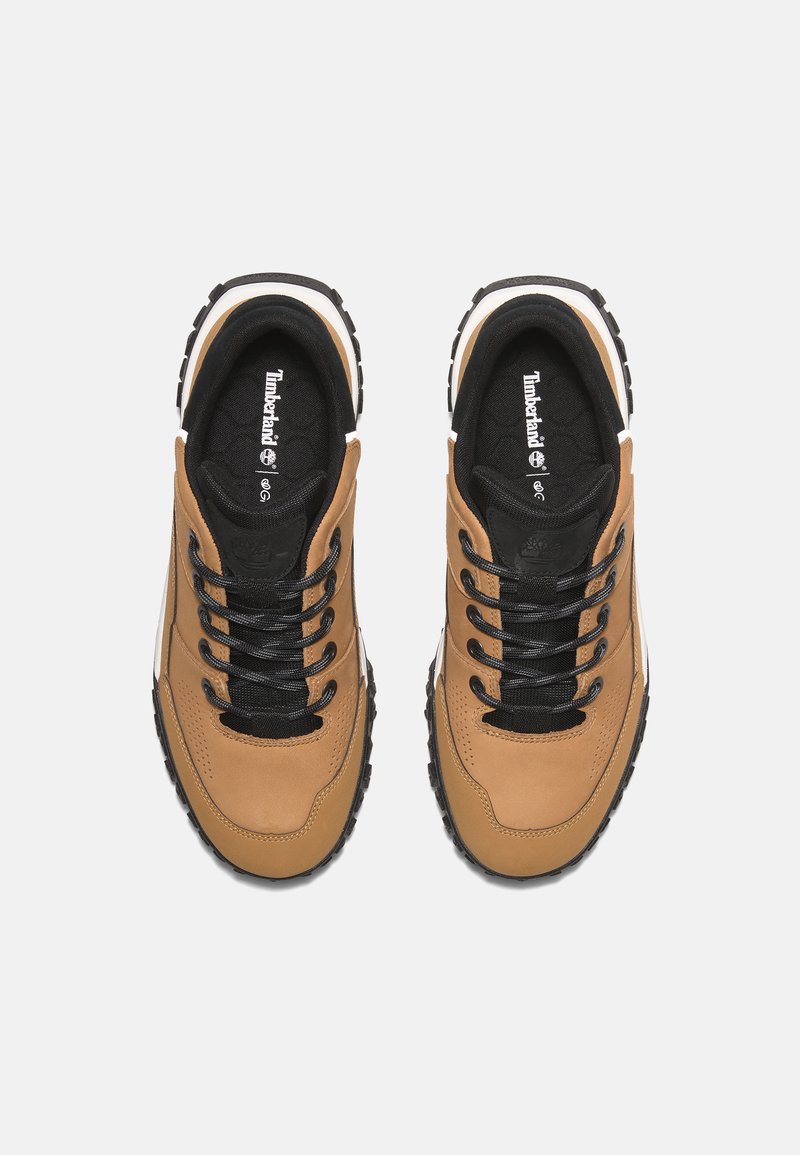 Bruine leren sneakers met zwarte veters, een gewatteerde kraag en een getextureerde zool. Bevat een logo op de tong en een contrasterende witte tussenzool.