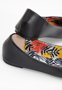 Ballerine nere con una superficie in pelle liscia, caratterizzate da un interno decorato con un motivo floreale multicolore e una punta arrotondata.