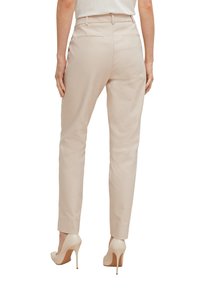 Harmaat beige -muotoiltutut housut, joissa on sileä pinta, korkea vyötärö, kapenevat lahkeet ja kaksi takataskua. Yhdistettynä ihonvärisiin korkokenkiin.