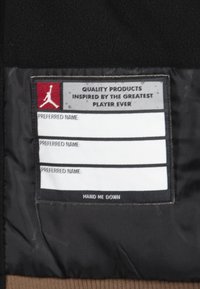 Etykieta na kurtkę z czarnym tłem z tkaniny, z białym i czerwonym tekstem. Zawiera miejsce na trzy preferowane imiona oraz napis "RĘKAWÓWKA".