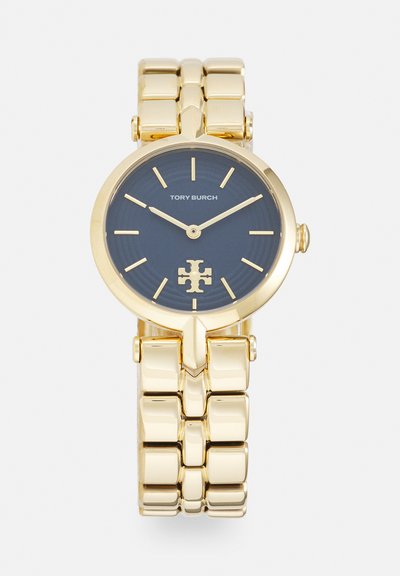 Orologio da polso in metallo color oro con quadrante blu, indici dorati minimalisti, logo Tory Burch alle ore 6 e bracciale a maglie dorato coordinato.