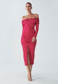 Červené šaty so spustenými ramenami s nariasenou textúrou, dĺžka do polovice stehien, s predným rozparkom a detailom na zips. Hladká tkanina a priliehavý strih.