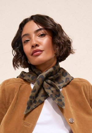 Brown suede jacket with a white shirt underneath. A green leopard print scarf tied around the neck, featuring black spots and a soft texture.