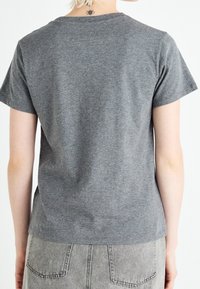 Camiseta gris de manga corta hecha de suave algodón con un sencillo cuello redondo. La tela tiene una textura lisa y una silueta relajada.