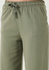 Leichte, olivgrüne, lässige Pants mit einem elastischen Bund und Kordelzug. Mit seitlichen Taschen und einem weichen, strukturierten Stoff.