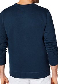 Granatowy sweter z okrągłym dekoltem, z długimi rękawami, ściągaczami przy rękawach oraz teksturowanym materiałem, wyeksponowany z tyłu.