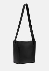 Czarna skórzana torba tote z regulowanym paskiem, gładką fakturą, prostokątnym kształtem i bocznymi szwami dla dodatkowego detalu.