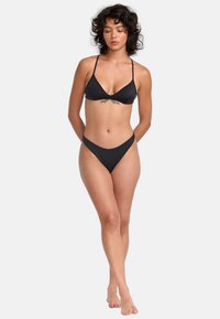 Black bikini set featuring a triangular top and low-rise bottoms. Smooth fabric with thin straps and minimal coverage.