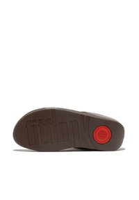 Bruine rubberen zool met een gestructureerd oppervlak, rode cirkelvormige accent en het reliëf merknaam "fitflop." Geen zichtbaar bovenstuk van de schoen.
